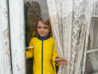 October 29, 2023,  Izium, Kharkivska oblast, Ukraine. Maria (4) is looking through the window of her house.