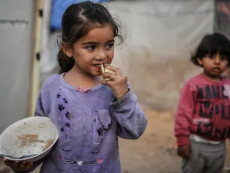 Israa eats a piece of bread in Khan Younis city.