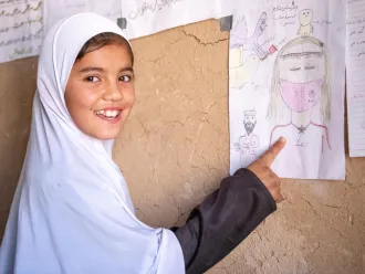 Nine-year-old Khadija shows one of her drawings in her community-based education class supported in Bagh-e-Jalal village, Daikundi province, central Afghanistan.