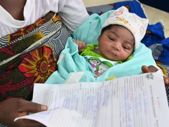 In Côte d'Ivoire, a baby sleeps while her mother holds her birth certificate. 