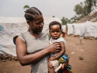 Nehema holds her daughter Queen, aged 2, after the girl's consultation at the mobile clinic set up by UNICEF and the Red Cross at the Lushagala site for displaced people, in North Kivu province, DR Congo, on 20 February 2024.