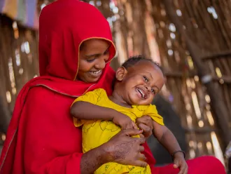 A mother holds her child lovingly as it laughs in her lap. 