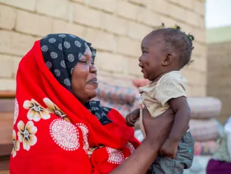 In Sudan, a smiling mother holds up her 10-month-old daughter.