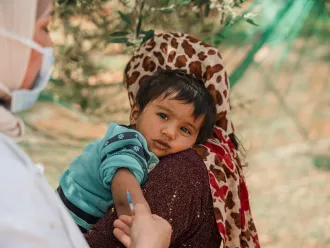 Un jeune enfant regarde pendant qu’il reçoit un vaccin dans un campement informel à Jarish, au nord de la Jordanie, lors d’une campagne de vaccination soutenue par l’UNICEF.