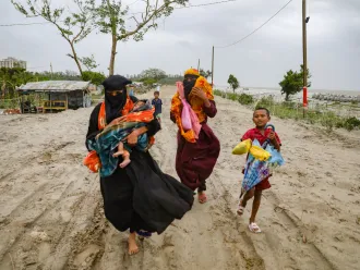 Inhabitants from the village of Panjupara are walking towards the shelter with their children and valuable household items during the rainfall in Kuakata, ahead of cyclone Remal's landfall in Bangladesh on May 26, 2024.