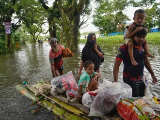 People travelling through the flood water on a make-shift raft, in search of shelter, in Feni.