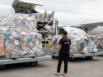 A UNICEF worker oversees humanitarian aid being offloaded from a cargo airplane.