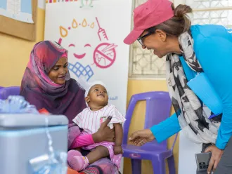 NICEF Sudan’s Chief of Health, shares a light moment with Adan Mohammed, 6 months, before she receives the malaria vaccine. Adan is the very first child to be vaccinated against malaria in Sudan.