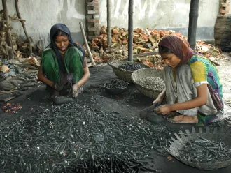 Two girls break used batteries to get pieces of metal out of them for recycling.