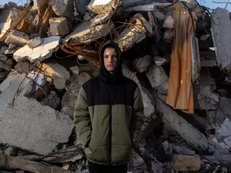 En Ukraine, un garçon se tient devant des décombres.