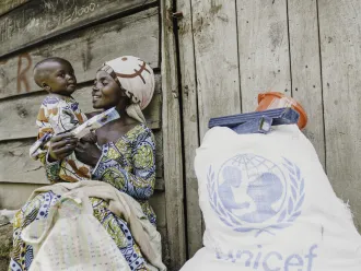 Judith, a mother of three, sits in front of her shelter with her child after receiving essential household items at the distribution site in Rugari, Rutshuru territory, North Kivu province, DR Congo, on 27 February 2025.