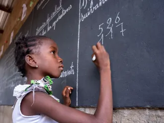 A girl writes on a blackboard in a Temporary Learning Space (TLS) in Fada N'Gourma, East Region, Burkina Faso