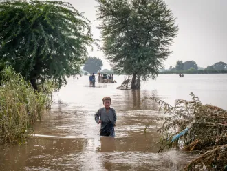 A boy walks across water in a flooded field.