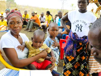 Mother holds her baby at a health centre with others gathered