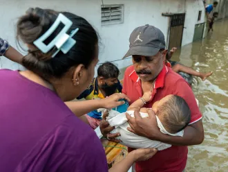 Des secouristes sri-lankais aident à transporter une famille bloquée avec un bébé à bord d'un bateau de sauvetage