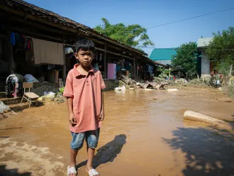 Un enfant se tient debout dans les eaux de l'inondation près de sa maison au Vietnam.