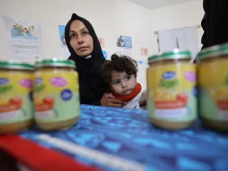 A mother holds a child while waiting to receive ready-to-use-complimentary-food.