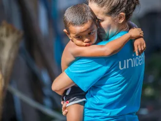 A UNICEF worker holds a toddler.