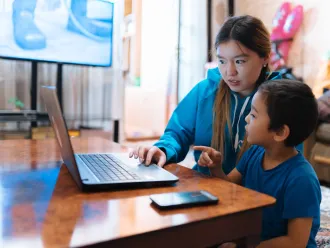 Aizaada, 21, a UNICEF Volunteer, transcribes lessons at home in Osh, Kyrgyzstan with her nephew, Aliyar.