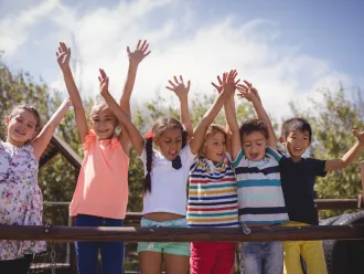 Children smiling with their hands raised in the air.