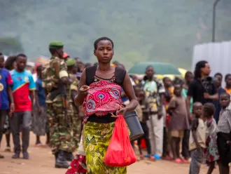 A woman carrying a baby walks through a crowded path    