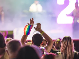 A crowd cheering and dancing at a Pride Festival. 