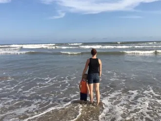 Bethany stands on a beach in Ghana with her son.