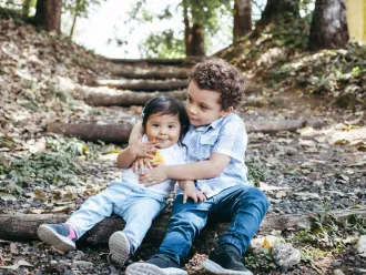 Two children are sitting together on the ground.