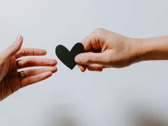 A person passes a small heart cut out to another person