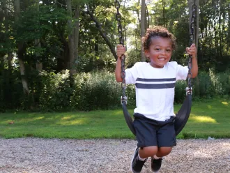 Young boy smiling on a swing set